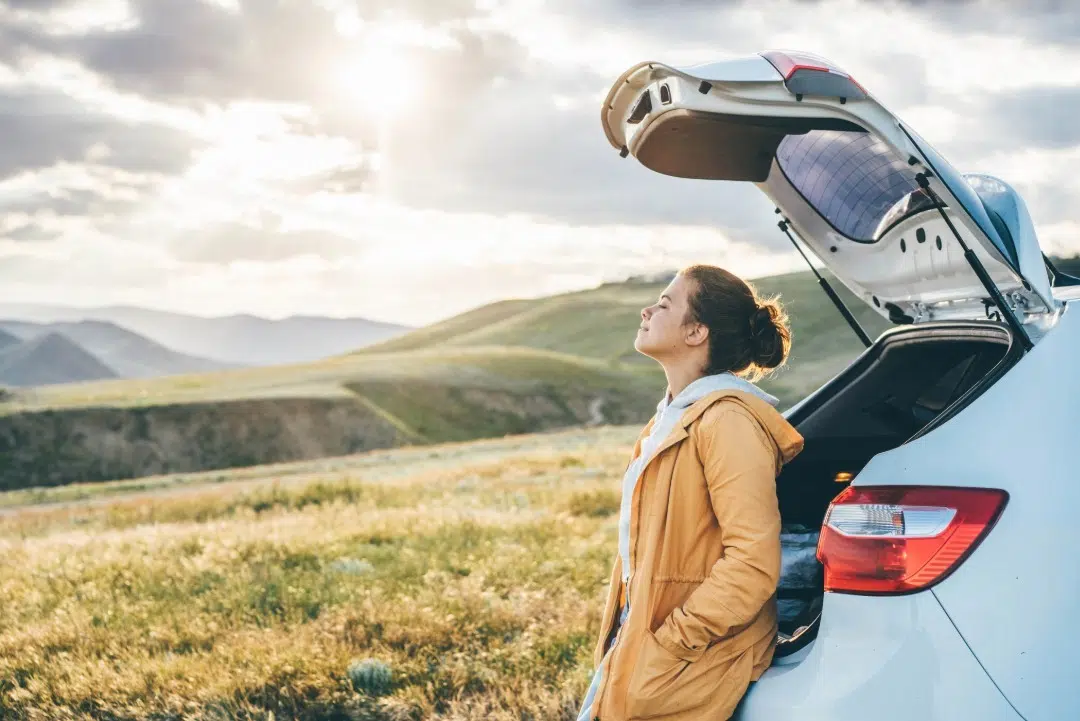 Woman relaxing outside a car by a field