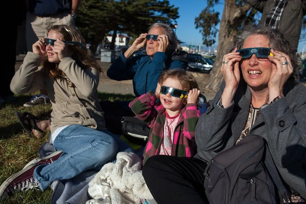 Family watching the solar eclipse with safety glasses