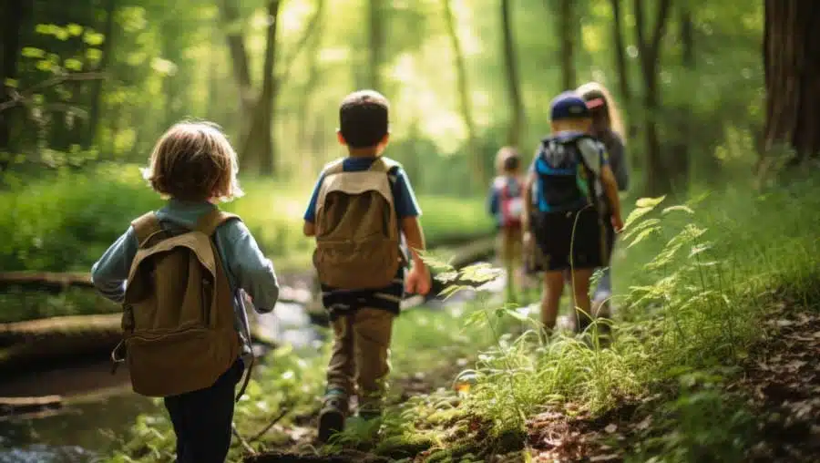 Kids wearing backpacks taking a nature walk in the woods